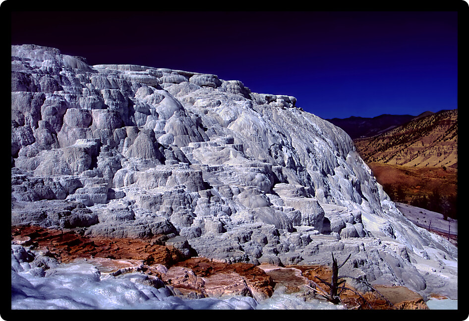 Bright sunlight shines on Canary Spring of the Mammoth Hot Springs in Yellowstone National Park.