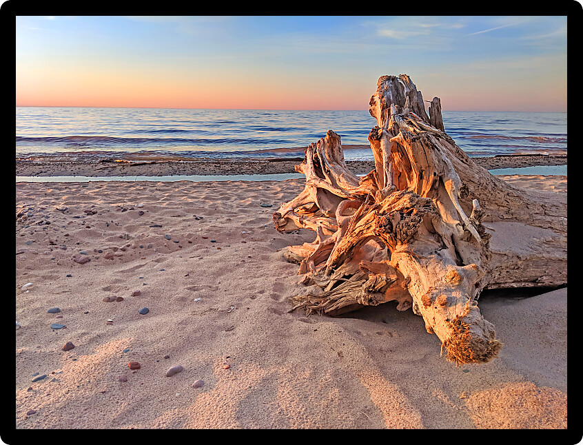 Driftwood and sandy Lake Superior Beach at sunset in northwoods Michigan.