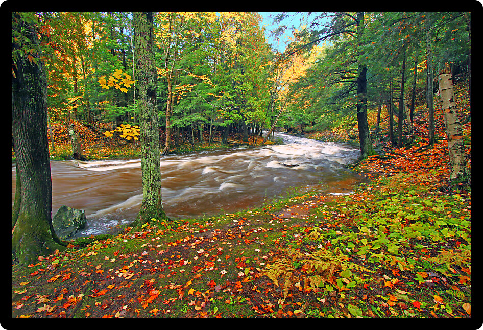 Rocky cascades of the Falls River flow through bright fall foliage in Baraga County Michigan.