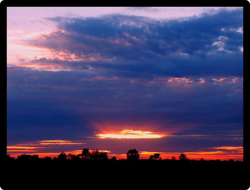 Rays of sunlight at sunset over the agricultural fields of rural Wisconsin.