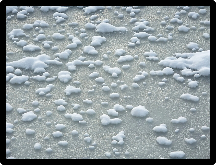 Patches of snow on the ice covered Kishwaukee River in northern Illinois.