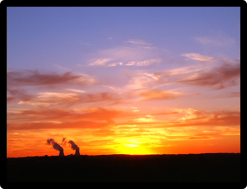 Vivid sunset over two giant cooling towers at a nuclear plant.