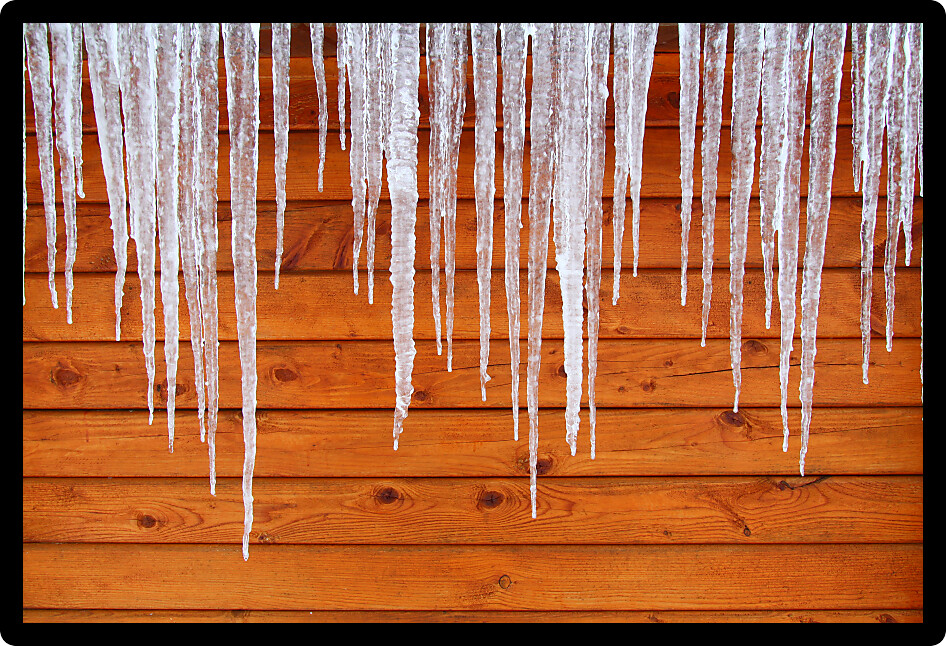 Icicles hang from a wood cabin in on a chilly winter day in northern America.