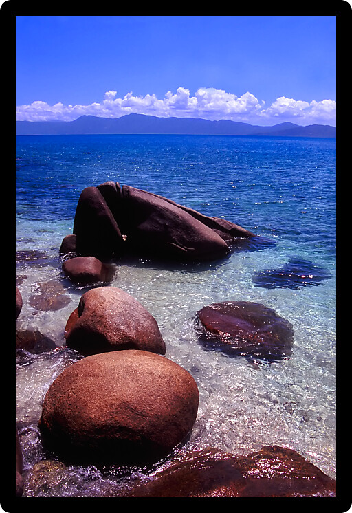 Light waves wash in among huge boulders on Nudey Beach of Fitzroy Island Australia.