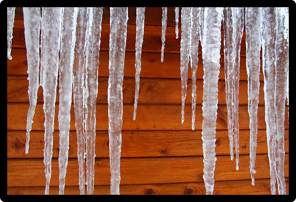 Icicles hang from a wood cabin in on a chilly winter day in northern America.