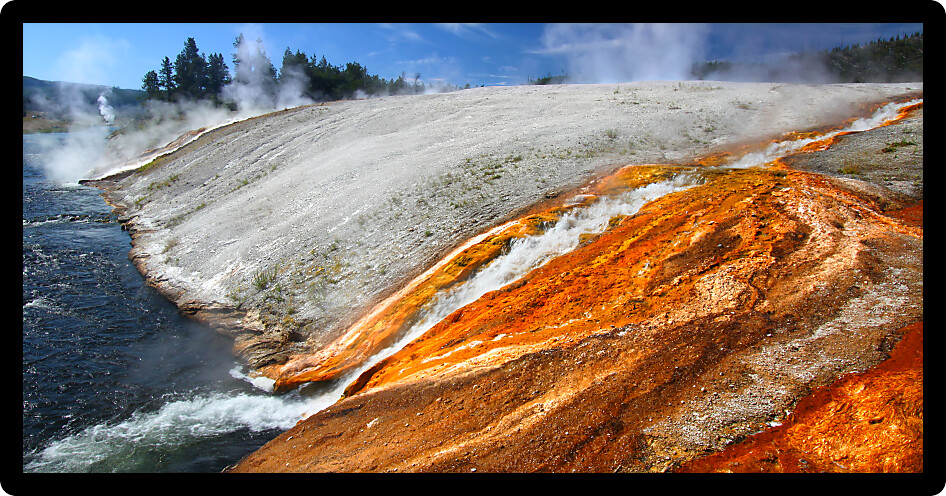 Hot water from the Midway Geyser Basin cascades into the Firehole River in Yellowstone National Park Wyoming.