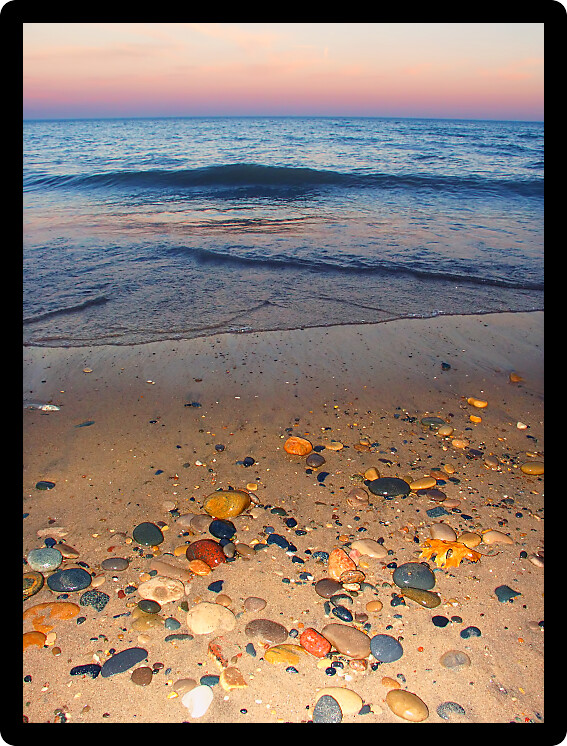Smooth stones dot the sand at sunset over Lake Michigan at Illinois Beach State Park.