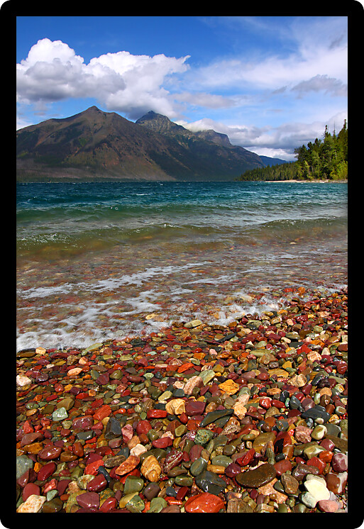 Small waves trickle through bright glacial rocks of Lake McDonald in Glacier National Park.