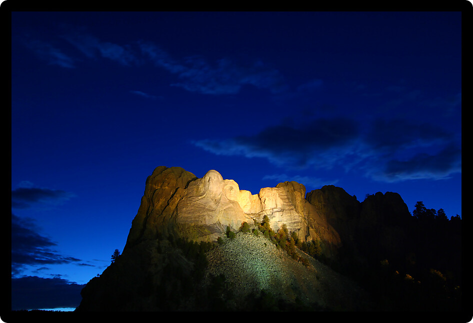 Mount Rushmore National Memorial illuminated under the twilight sky in South Dakota.