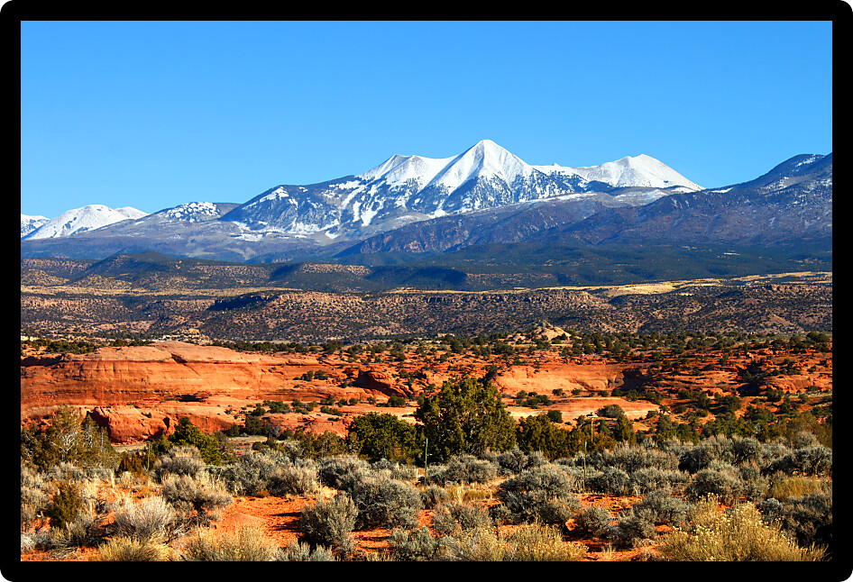 Snowcapped Mount Tukuhnikivatz of the Monti-La Sal National Forest rises above the red rock landscape in Utah.