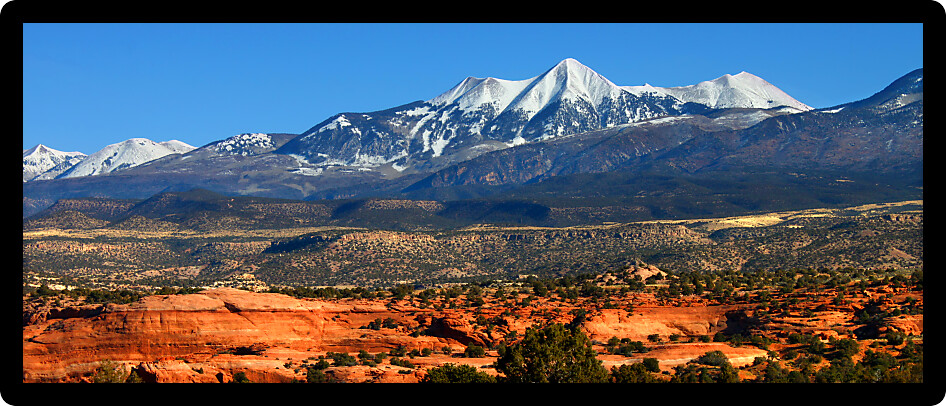 Snowcapped Mount Tukuhnikivatz of the Monti-La Sal National Forest rises above the red rock landscape in Utah.