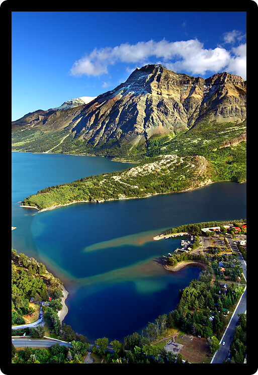 Sweeping view over blue waters and rugged mountain peaks of Waterton Lakes National Park in Canada.