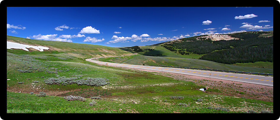 Panorama of a winding road through high elevations of the Bighorn National Forest in Wyoming.