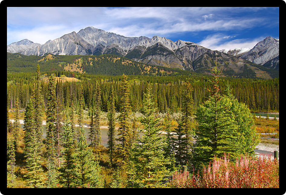 Mountains of the Canadian Rockies rise beyond the Bow River in Canada.